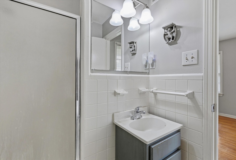 Bathroom vanity with an integrated sink and chrome faucet, set against white tile wainscoting