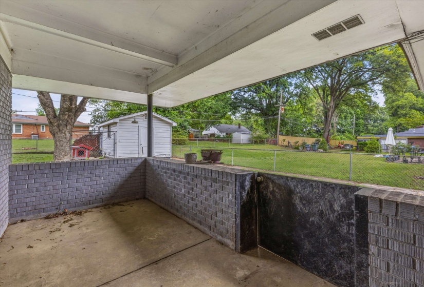 Covered patio featuring concrete flooring and a gray brick half-wall