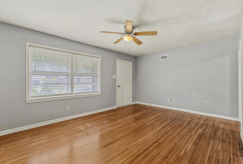 Room featuring wood-finish flooring, a ceiling fan, a window with blinds, and light-colored walls