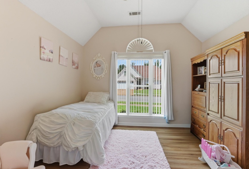 Vaulted ceiling room featuring wood-finish flooring and a large window with vertical blinds