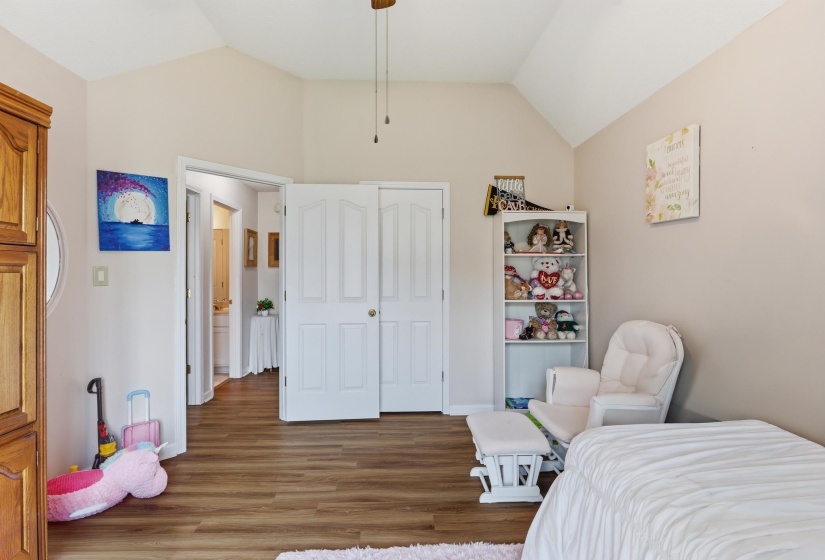 Wood-finish flooring with vaulted ceilings, neutral wall tones, and white interior doors