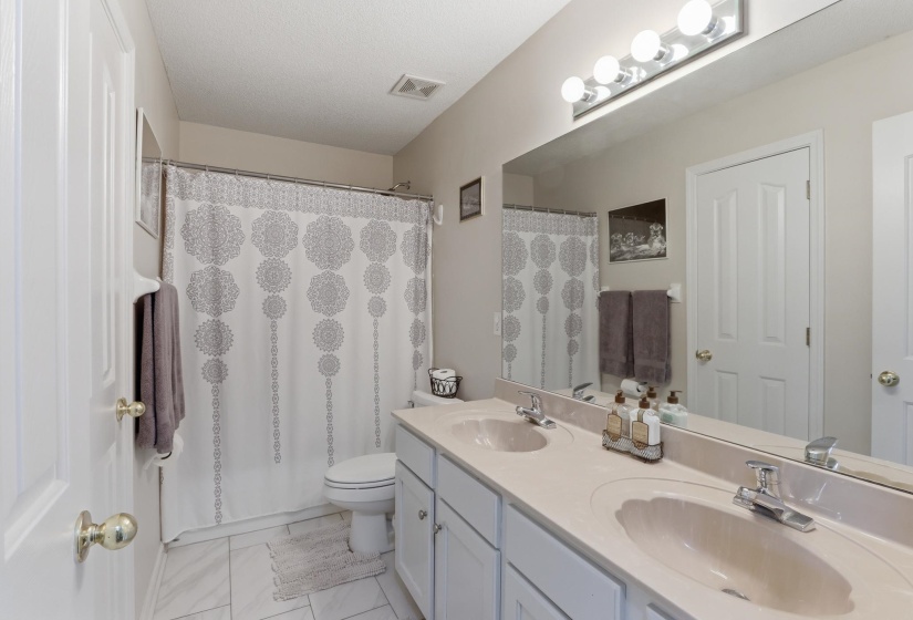 Bathroom featuring a dual vanity with integrated sinks, a wide mirror, and a five-bulb vanity light fixture