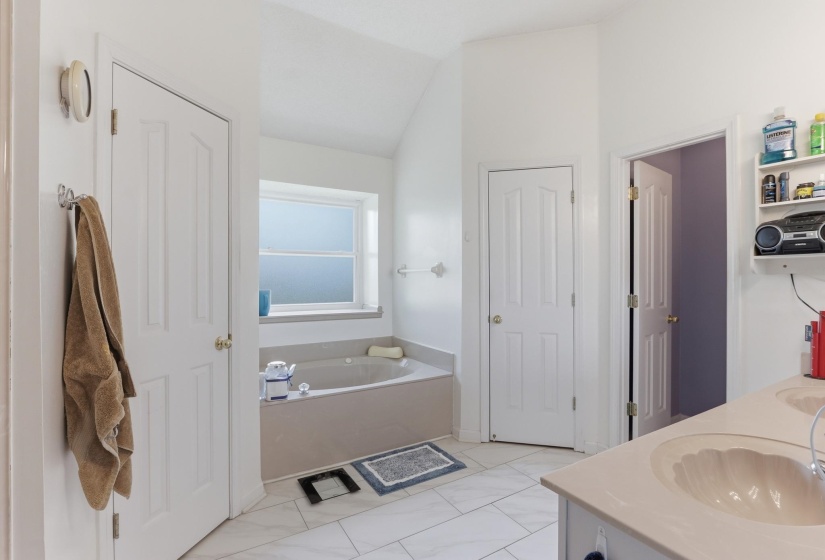Bathroom featuring a built-in tub with a privacy window, white panel doors, and tile flooring