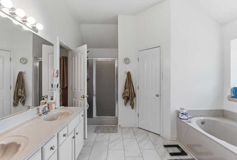 Bathroom featuring a dual vanity with integrated sinks, white cabinetry, and a large mirror with strip lighting