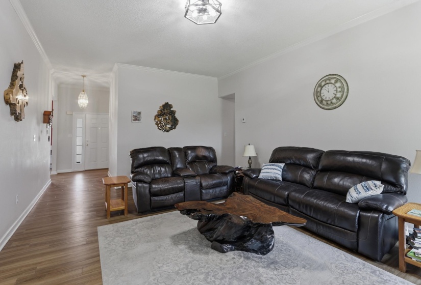 Spacious living area featuring wood-finish flooring, light-toned walls, and crown molding