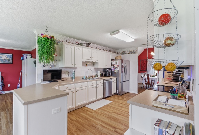 Kitchen featuring white cabinetry, light countertops, wood-finish flooring, and stainless steel appliances