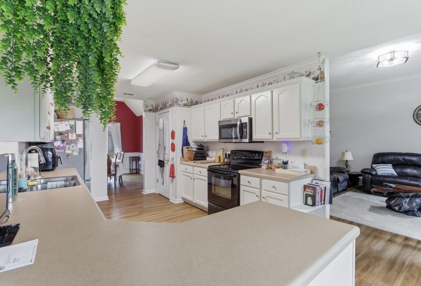 Kitchen featuring white cabinetry, black appliances, a double basin sink, and a peninsula countertop