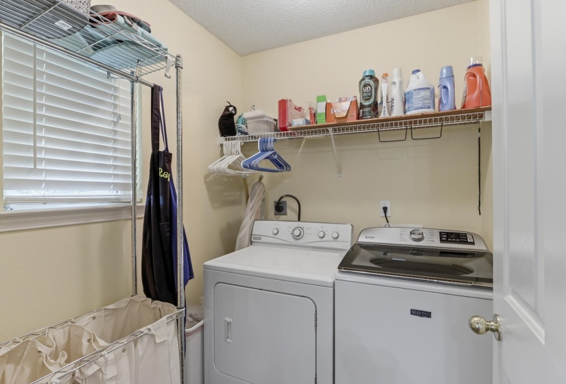 Dedicated laundry area featuring a window with blinds, upper wire shelving, and neutral wall paint