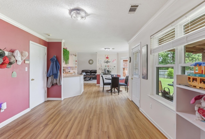 Open-concept living area featuring wood-finish flooring, white trim, and a kitchen with white cabinetry and a breakfast bar