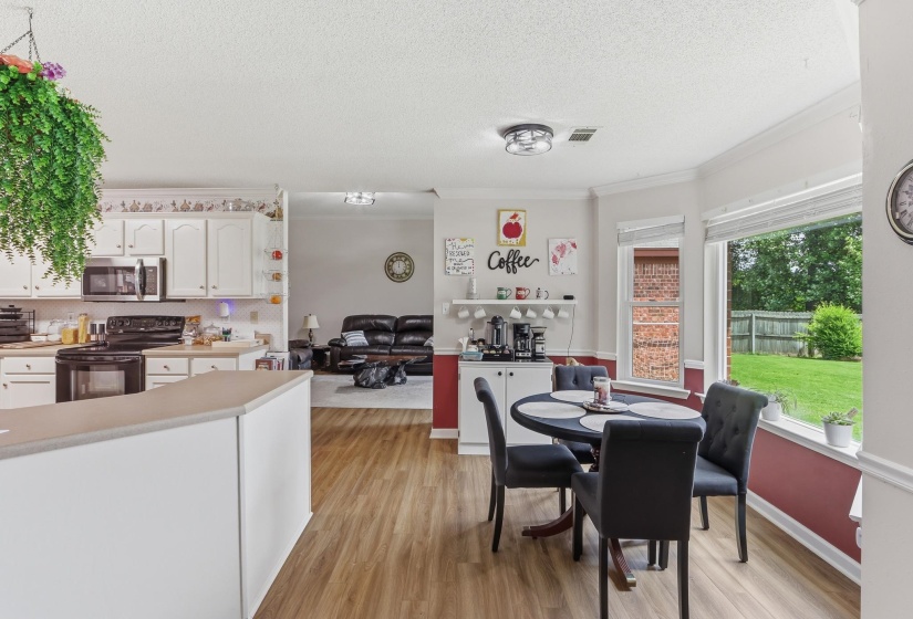 Open-concept kitchen and dining area featuring white cabinetry, light-toned countertops, and wood-finish flooring
