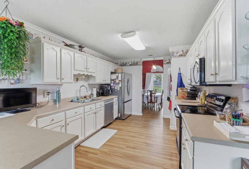 Kitchen featuring white cabinetry, light-toned countertops, wood-finish flooring, and a stainless steel refrigerator