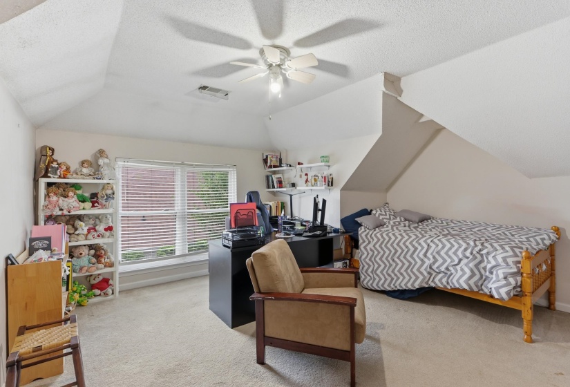 Carpeted room with a ceiling fan, sloped ceilings, and a double window with horizontal blinds