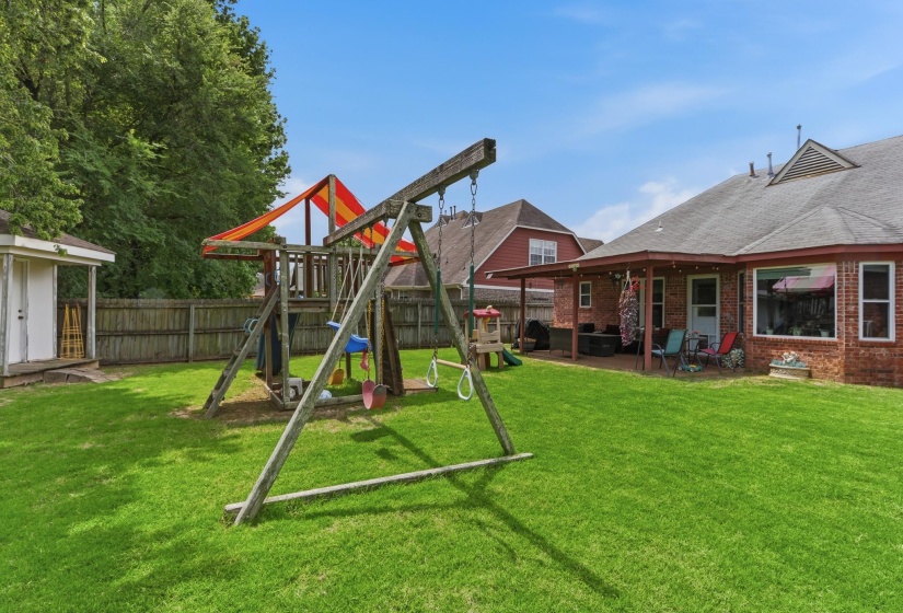 Expansive backyard featuring a lush lawn, privacy fencing, and a detached storage shed