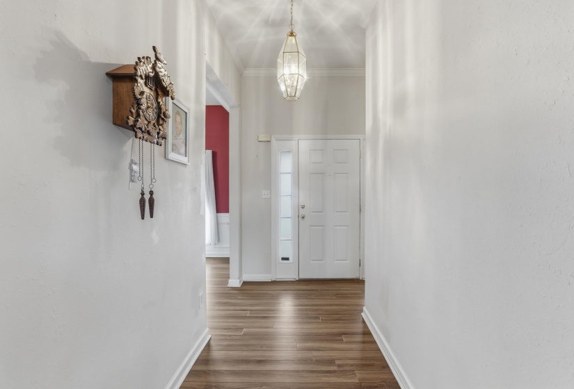 Entryway featuring wood-finish flooring, a white paneled door with sidelight, a decorative pendant light, and white baseboards