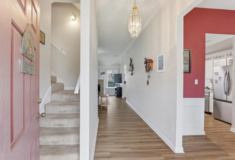 Entryway featuring wood-finish flooring, a carpeted staircase, and a decorative pendant light fixture