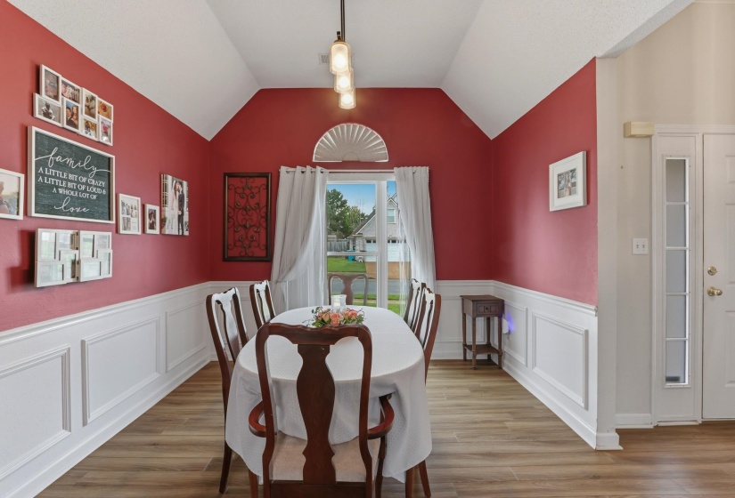 Dining area featuring a vaulted ceiling and wood-finish flooring