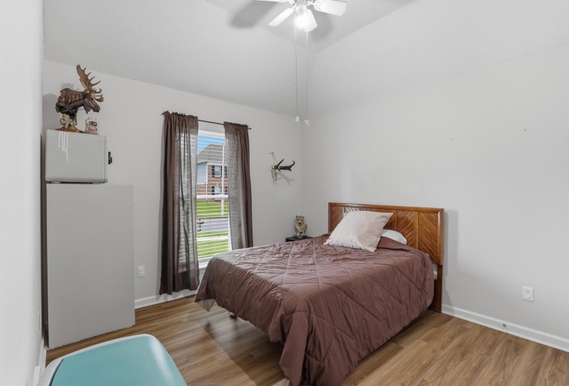 Bedroom featuring wood-finish flooring, a ceiling fan with light fixture, and a window with blinds