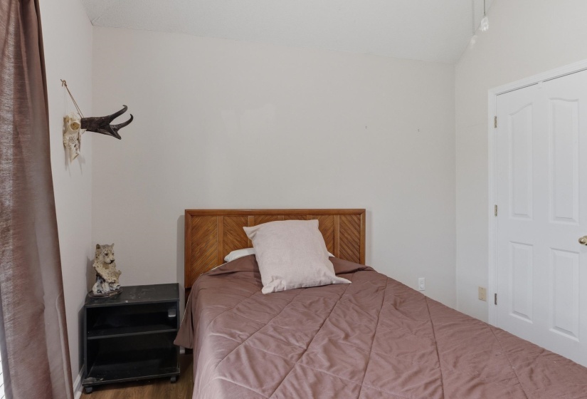 Bedroom featuring light neutral wall paint, wood-finish flooring, and a white two-panel door
