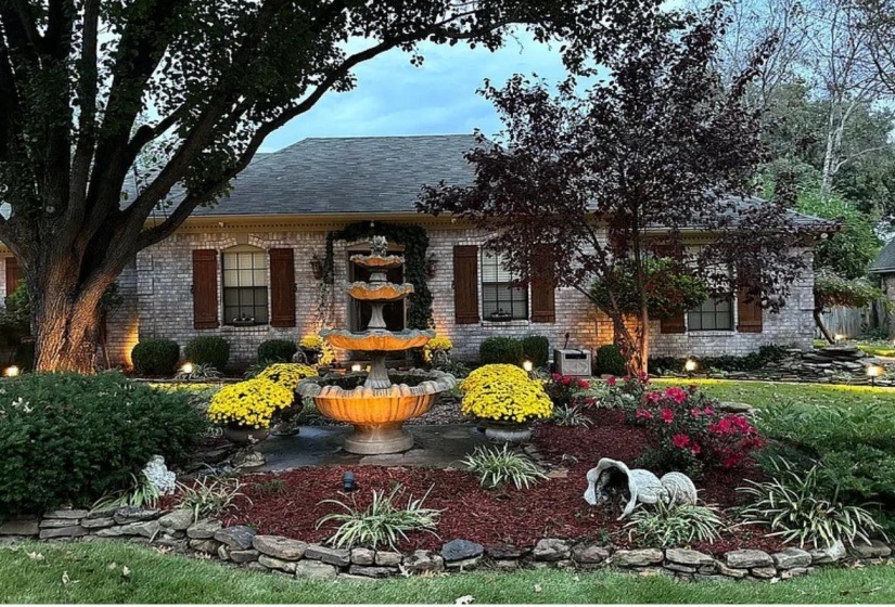 Brick facade residence featuring a multi-tiered fountain and extensive landscaping