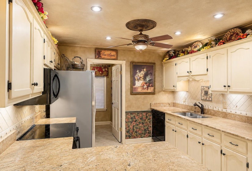 Kitchen featuring light-toned cabinetry, granite-finish countertops, and a tile backsplash