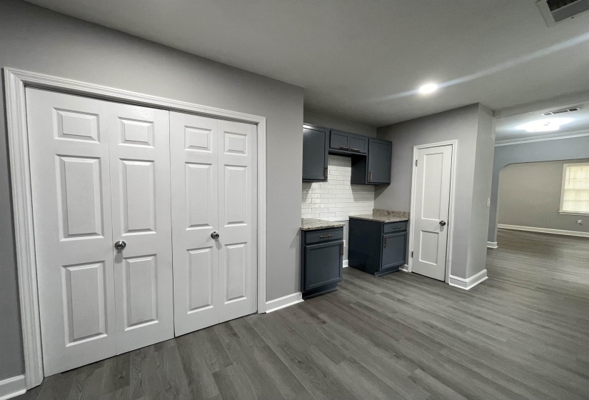 Kitchenette featuring dark cabinetry with a tile backsplash and light-toned countertops