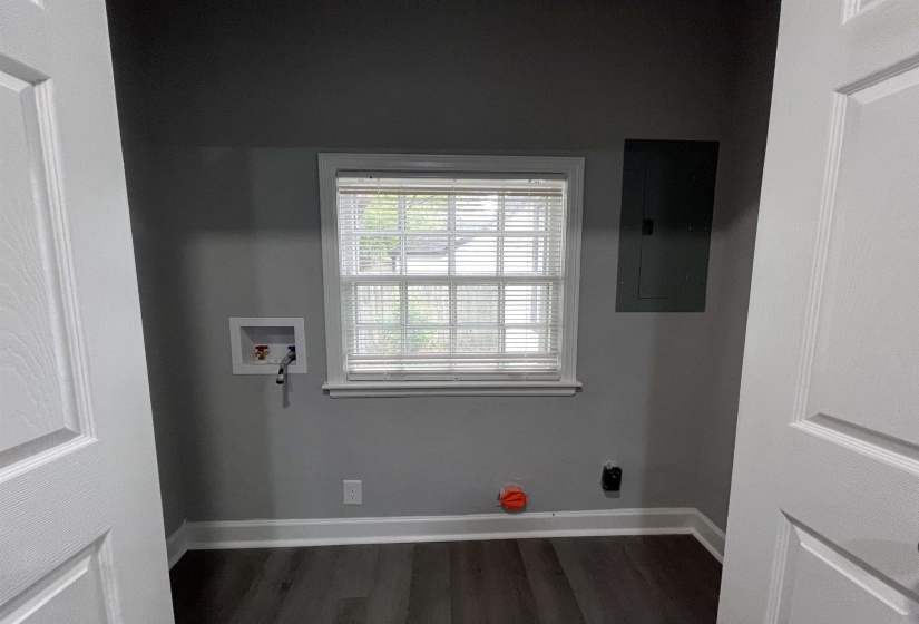 Dedicated utility area featuring a window with blinds, wood-finish flooring, and light gray walls