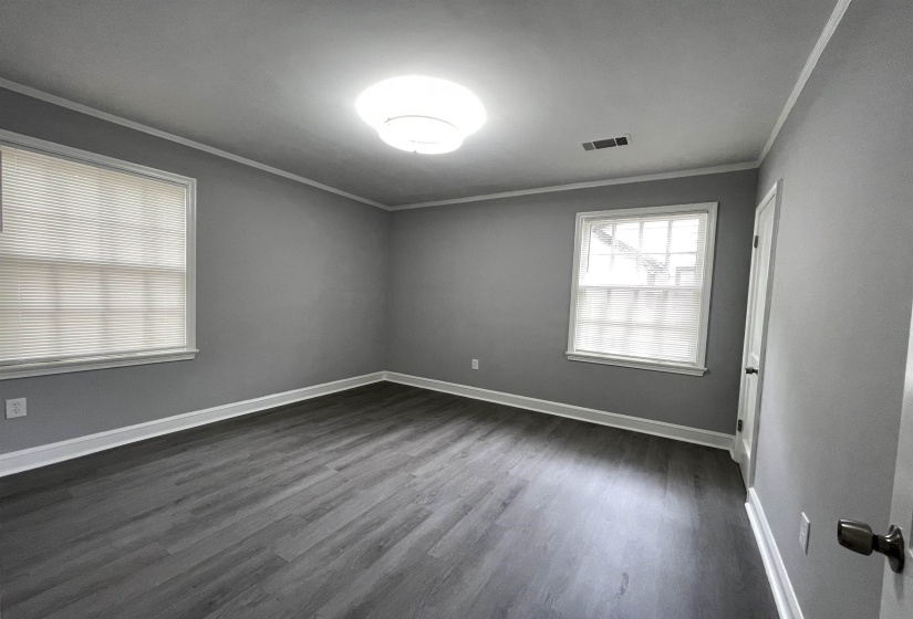 Spacious room featuring wood-finish flooring and two large windows