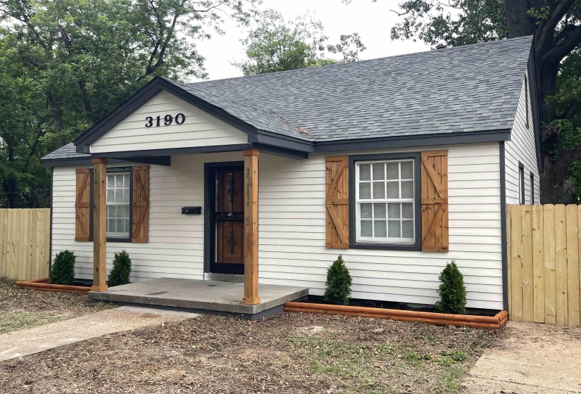 White horizontal siding facade with dark trim, a covered porch entry, and a new privacy fence