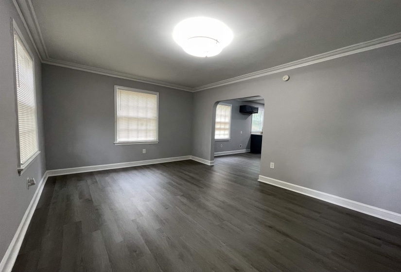 Spacious interior room featuring wood-finish flooring, light gray walls, and crown molding