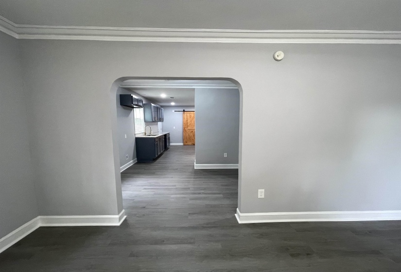 Archway opening to a kitchen featuring dark wood-finish flooring, dark cabinetry, and a sliding barn door