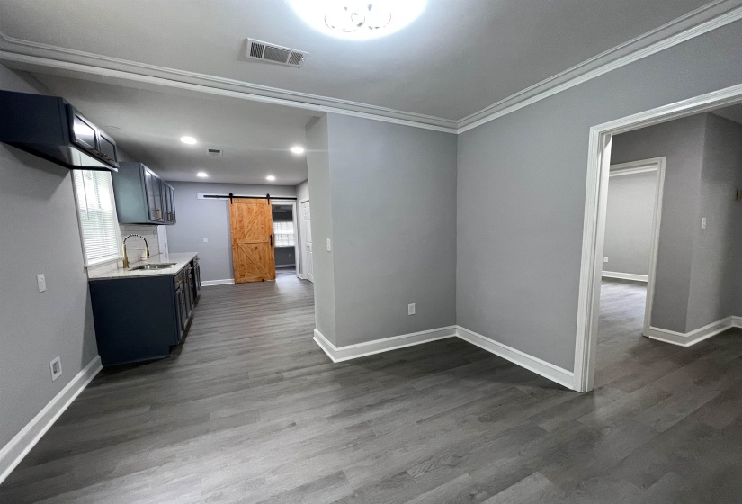 Open-concept living area featuring wood-finish flooring, crown molding, and recessed lighting