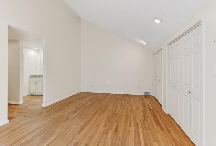 View of the primary suite looking towards the private full bath and hallway that leads into this quiet space.