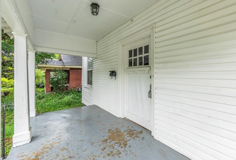 Covered porch featuring white siding, a grid-paned entry door, and an overhead light fixture