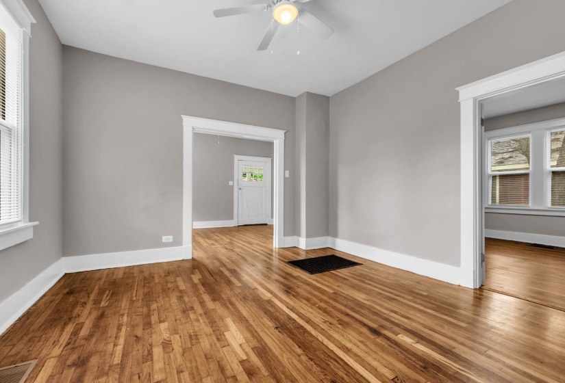 Spacious interior room featuring wood-finish flooring, light gray wall paint, and white trim