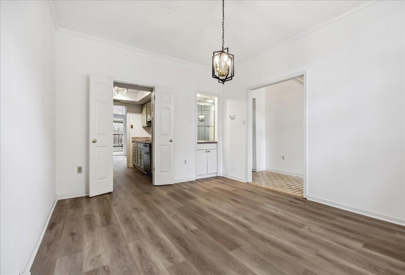 Spacious interior featuring wood-finish flooring, a built-in display cabinet with mirrored backing, and an open doorway to an adjacent room with patterned tile flooring