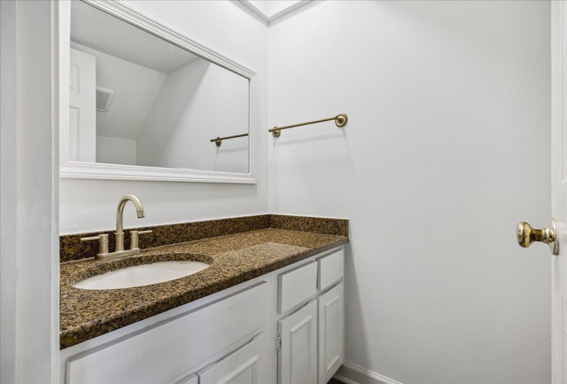 Bathroom vanity featuring a speckled countertop, undermount sink, and brushed nickel faucet