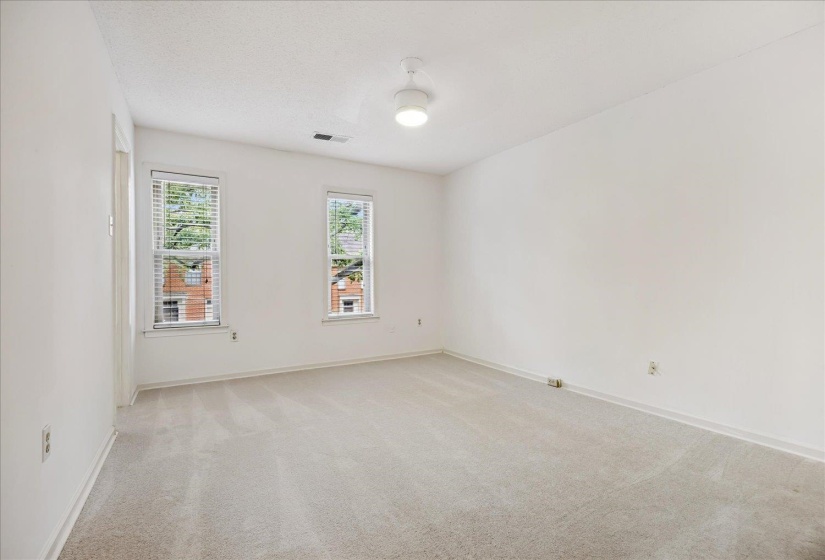 Carpeted interior space featuring white walls and two windows with blinds