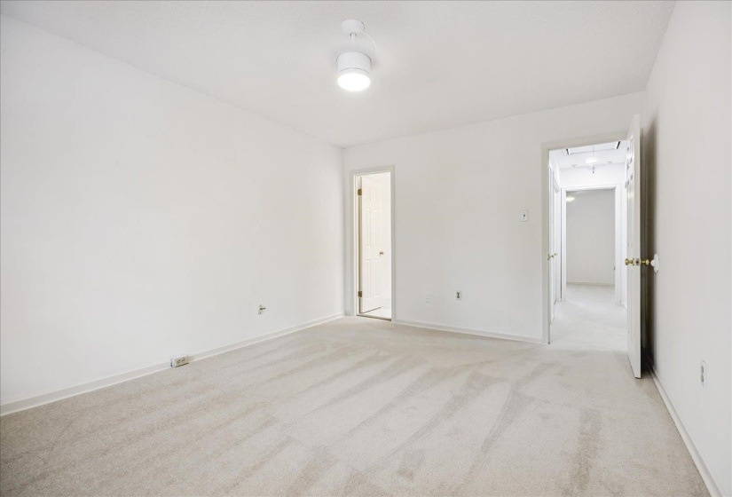 Neutral tone wall finishes, light-colored carpeting, and overhead flush-mount lighting create a bright interior