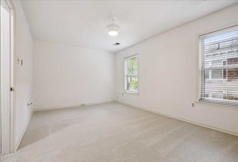 Carpeted room featuring two windows with horizontal blinds, a ceiling-mounted light fixture, and white painted walls