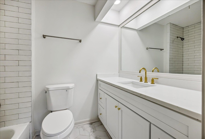 Bathroom featuring a white vanity with a rectangular undermount sink, brass-finish fixtures, and a large mirror
