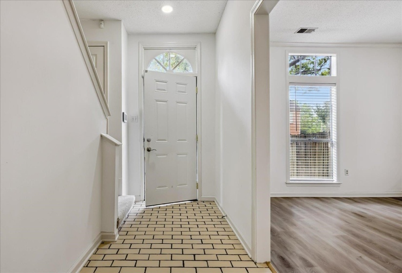 Entryway featuring light-colored brick-patterned flooring and a multi-panel door with an arched transom window