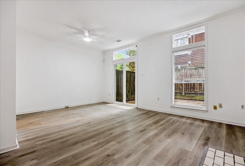 Spacious room featuring wood-finish flooring, white walls, and crown molding