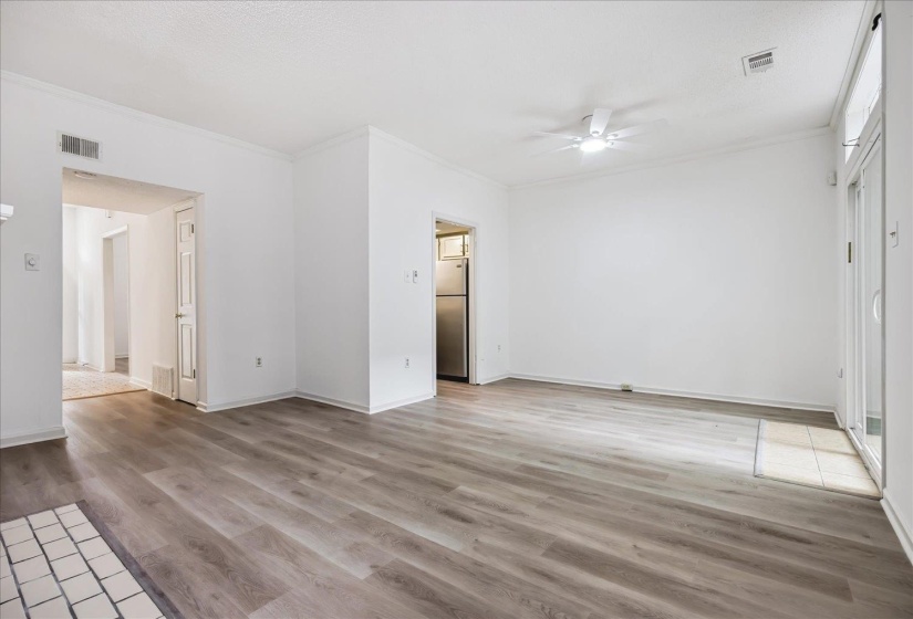 Spacious living area featuring wood-finish flooring, white walls, and crown molding