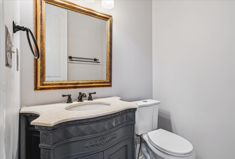 Bathroom featuring a decorative vanity with an integrated sink, light-toned countertop, and antique brass faucet fixtures
