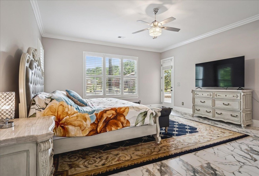 Spacious room featuring elegant crown molding, a ceiling fan with integrated lighting, and a glass-paneled door