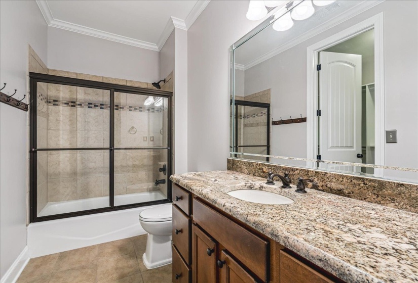 Bathroom featuring a spacious vanity with an undermount sink, granite countertop, and dark-finish cabinetry