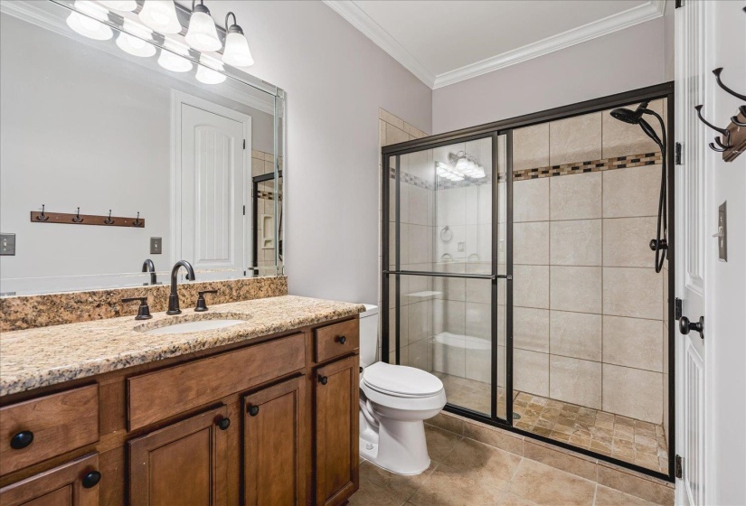 Bathroom featuring a wood-finish vanity with a light-toned countertop, a rectangular undermount sink, and a framed mirror