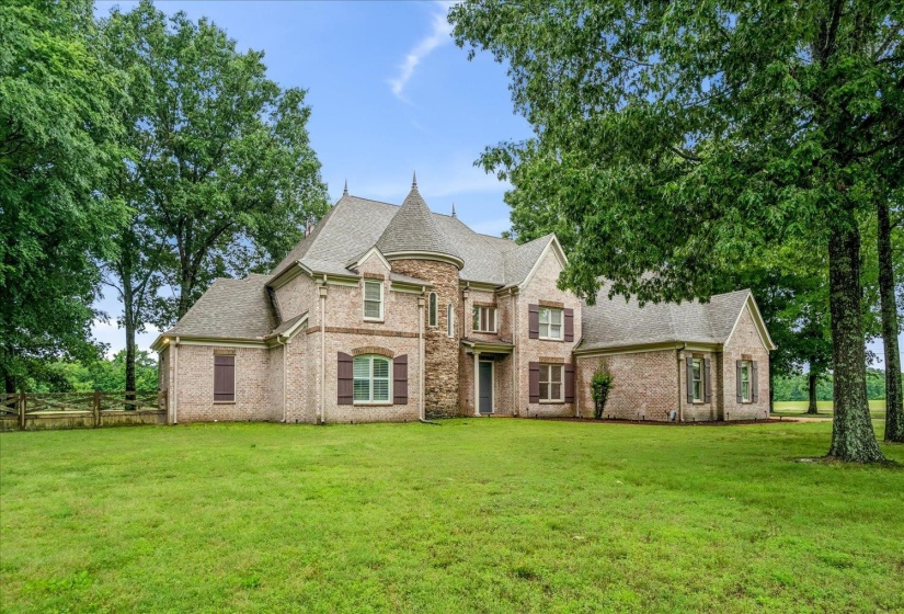 Brick exterior with a stone turret, multiple gables, and dark louvered shutters