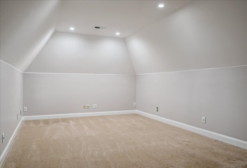 Carpeted room with sloped ceilings, recessed lighting, neutral paint, and white baseboards
