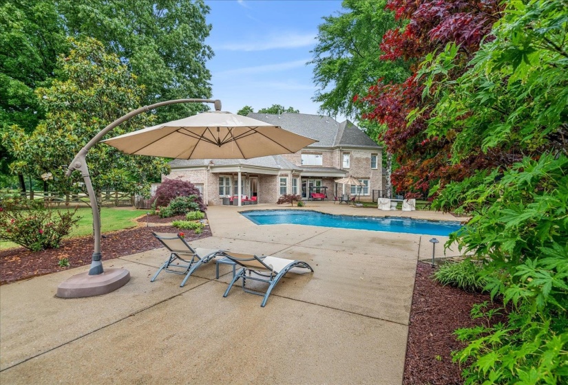Rear exterior featuring a swimming pool, expansive concrete patio, and a covered porch